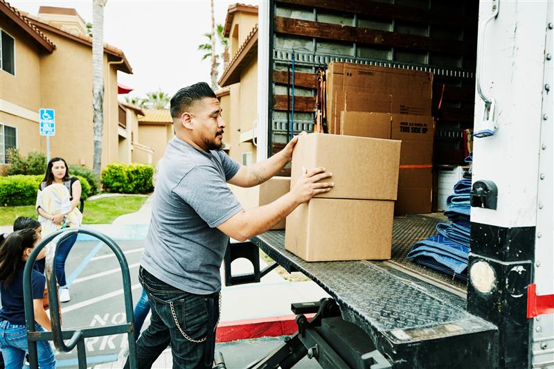 Man loads boxes into the back of a moving truck.